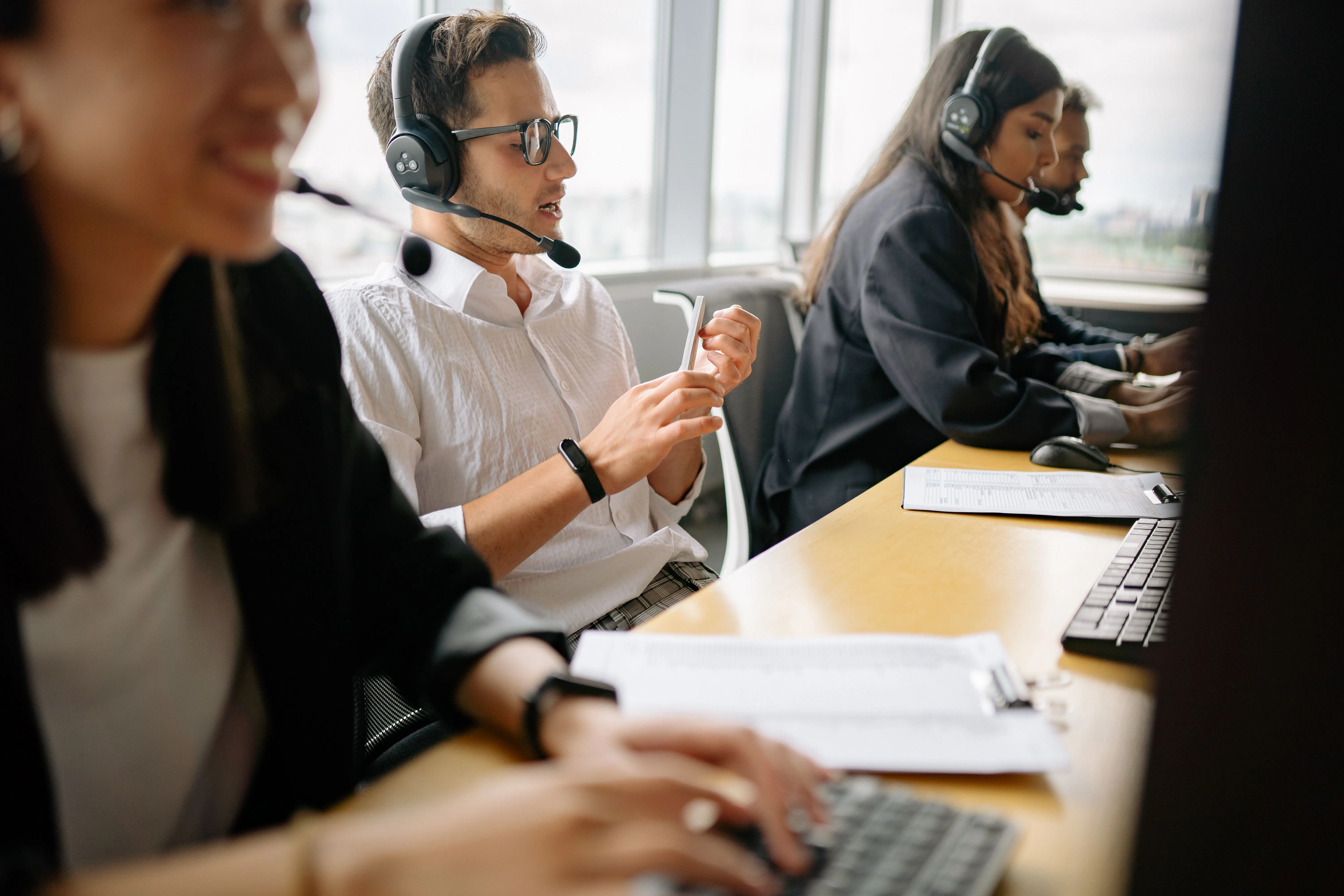 Call center agents wearing headsets working at a row of desks