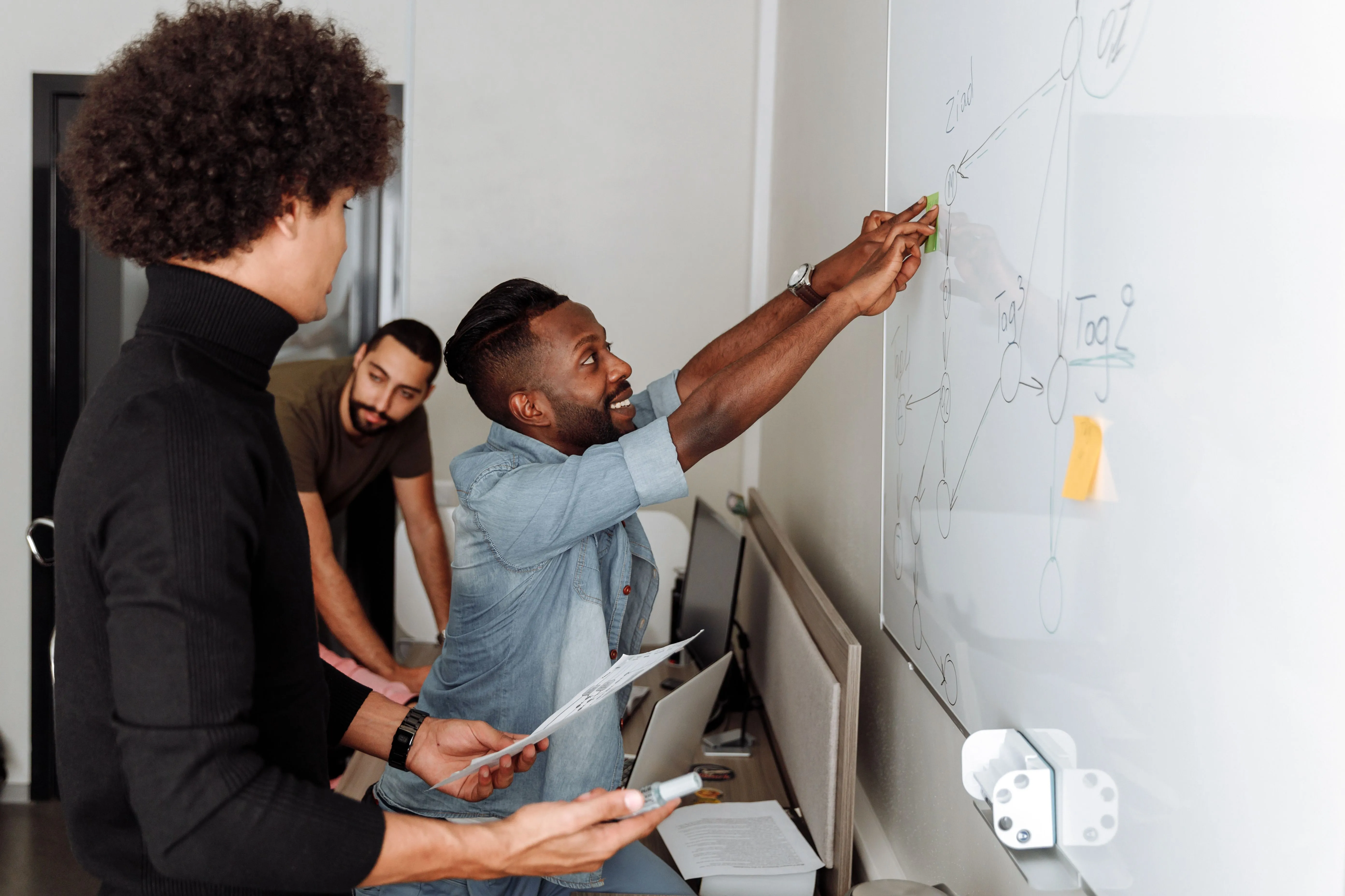 Colleagues mapping a process diagram with sticky notes on a whiteboard
