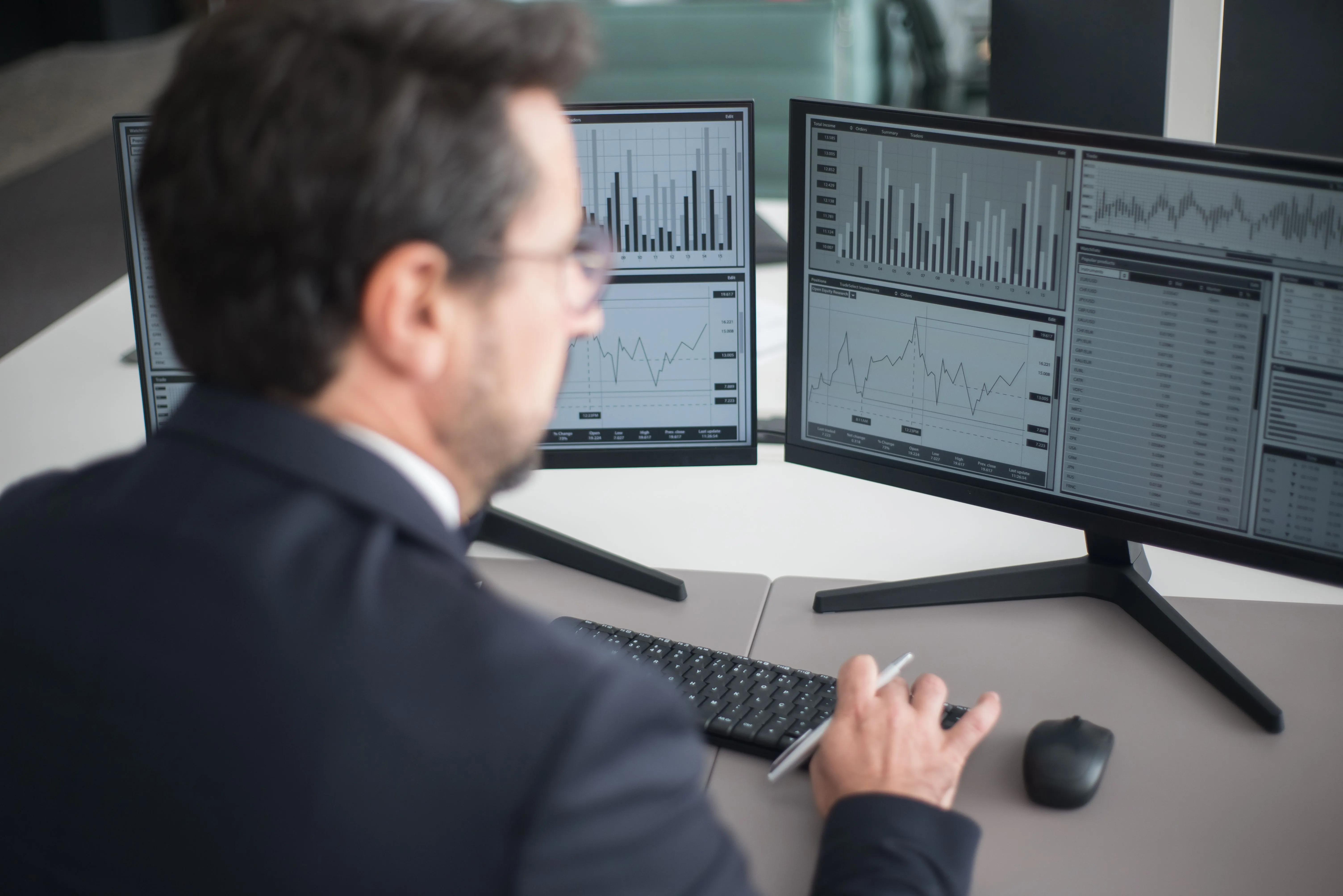 A person monitoring analytics dashboards across dual desktop monitors